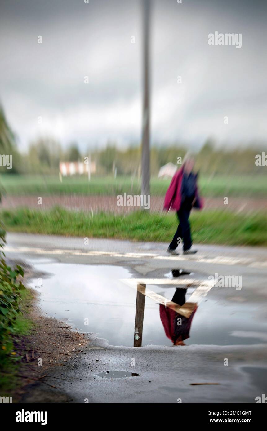 Abstraktes Bild einer Frau, die auf der nassen Landstraße ellingham norfolk england läuft Stockfoto