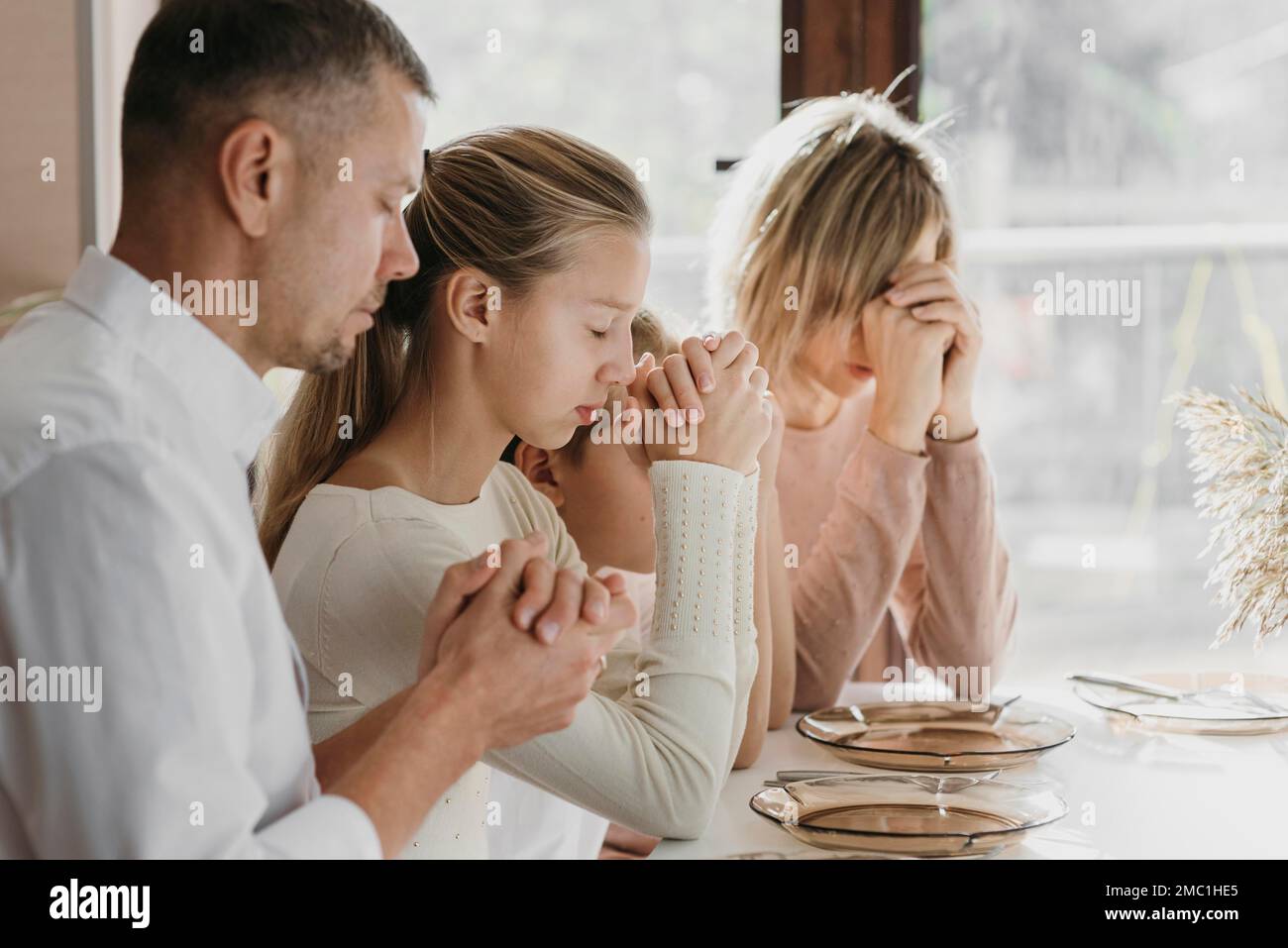 Schöne Familie beten zusammen vor dem Essen Stockfoto