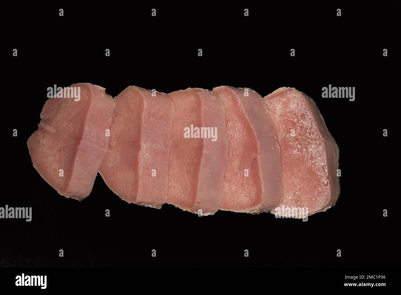 Gepökelte, gekochte und geschnittene Schweinenzunge, Lebensmittelfotografie mit schwarzem Hintergrund Stockfoto