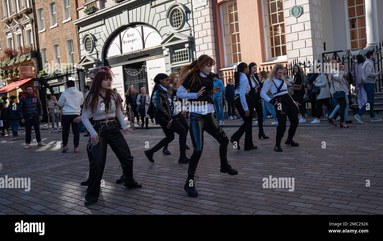 London - 02 27 2022: Mädchen tanzen weiter mit einer dritten Bewegung des Shuffle-Tanzes in covent Garden, mit Menschen um sich herum Stockfoto