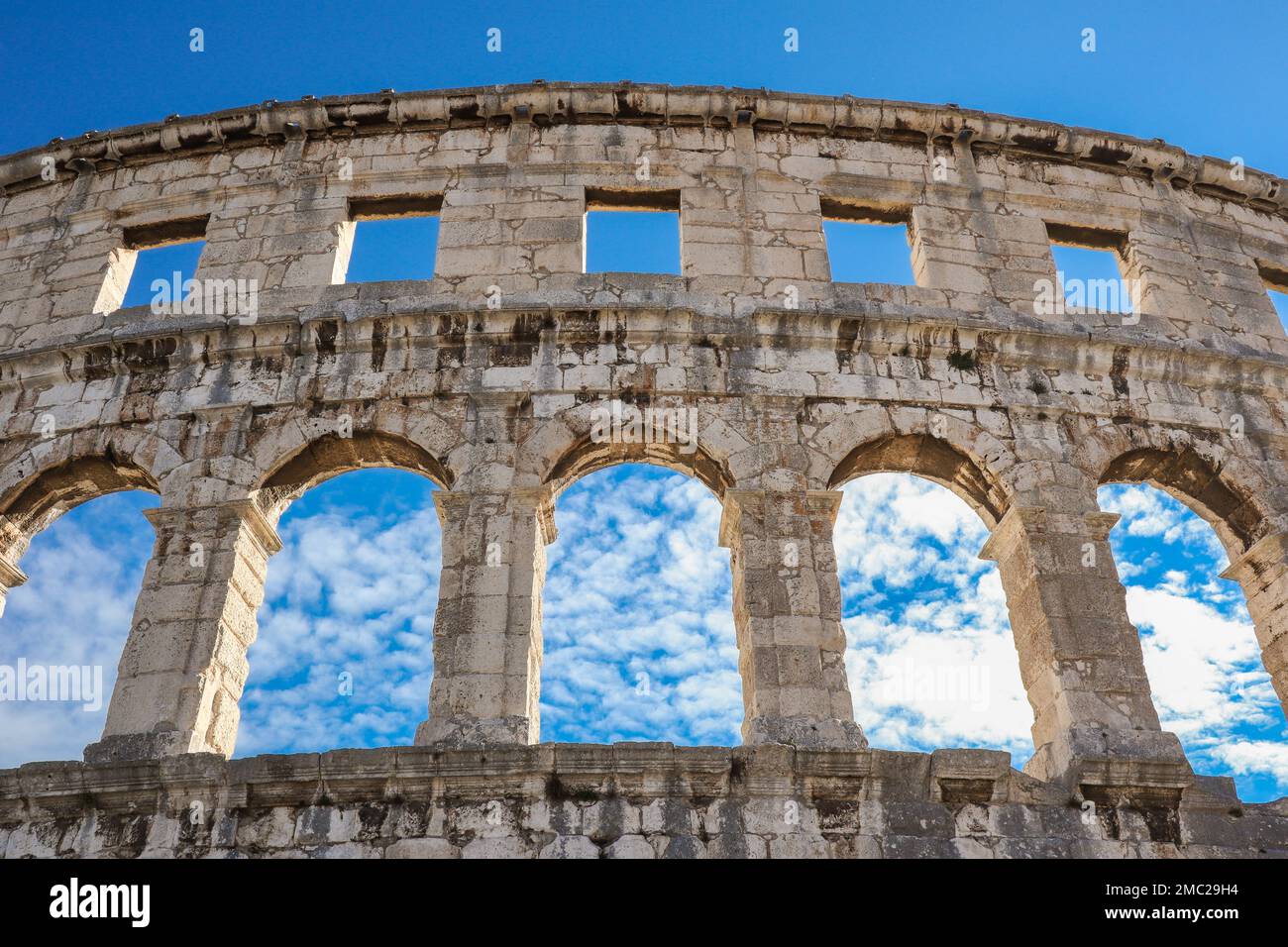 Blick unter die Pula Arena in Kroatien. Wunderschönes berühmtes römisches Amphitheater in Istrien mit blauem Himmel und Wolken am Sommertag. Stockfoto