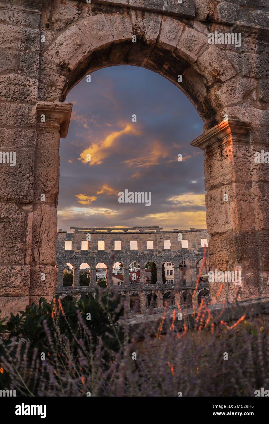 Vertikaler Blick auf die Pula Arena mit dramatischem Himmel. Außenansicht des römischen Amphitheaters während der Goldenen Stunde und des Sonnenuntergangs in Kroatien. Stockfoto