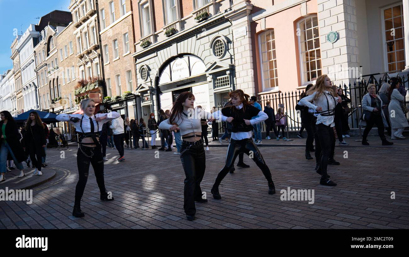 London - 02 27 2022: Mädchen tanzen weiter mit der vierten Bewegung des Shuffle-Tanzes in covent Garden, mit Menschen um sich herum Stockfoto