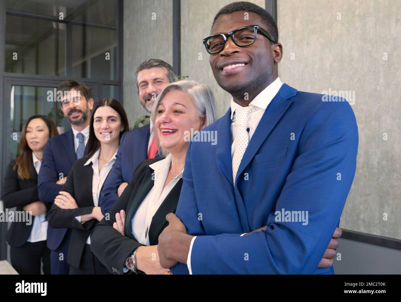 Vielfältiges Team glücklicher junger Menschen, die zusammenstehen. Multiethnische Gruppe von Kollegen, die in der Schlange stehen, die Arme gefaltet haben und lächeln. Konzepte der Teamarbeit Stockfoto