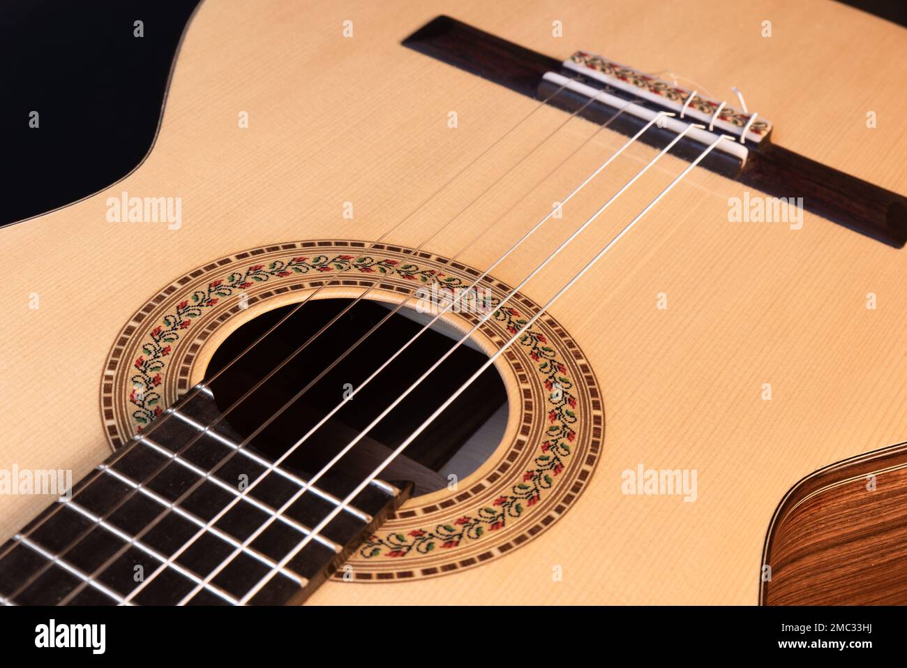 Klassische Gitarrenspitze isoliert auf schwarzem Hintergrund mit einer wunderschönen Mosaikrosette, Blick von der Oberseite. Wunderschönes brasilianisches Holz - Pau Ferro Stockfoto