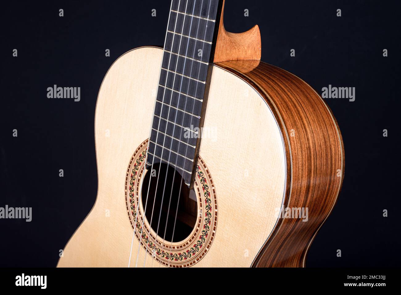 Klassische Gitarrenspitze isoliert auf schwarzem Hintergrund mit einer wunderschönen Mosaikrosette, Blick von der Oberseite. Wunderschönes brasilianisches Holz - Pau Ferro Stockfoto