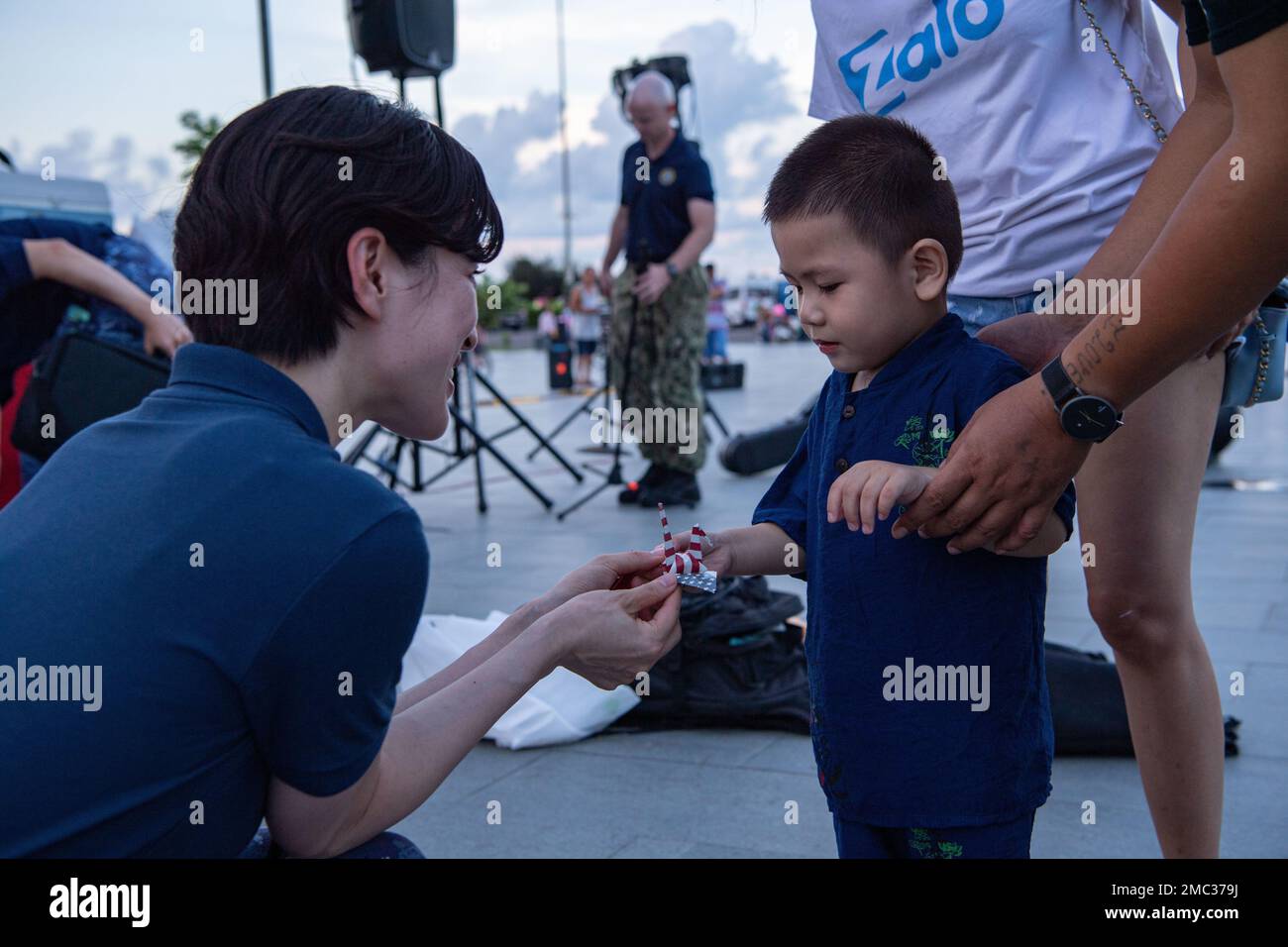 220624-N-NC885-1016 PHU YEN, VIETNAM (24. Juni 2022) – der japanische Soldat der Marine Self-Defense Force 2. Class Yukari Miyake, ein Sänger, der derzeit die USA begleitet Pacific Fleet Band im Rahmen der Pacific Partnership 2022 schenkt ein Kind einen Origami-Schwan, bevor es im April PP22 im Park am 1. Platz ein landesweites Outreach-Event veranstaltet. Die Pazifikpartnerschaft ist die größte multinationale Mission zur Vorbereitung auf humanitäre Hilfe und Katastrophenhilfe, die jährlich im Indo-Pazifik durchgeführt wird. Sie ist seit 17. Jahren Teil der Partnerschaft. Stockfoto