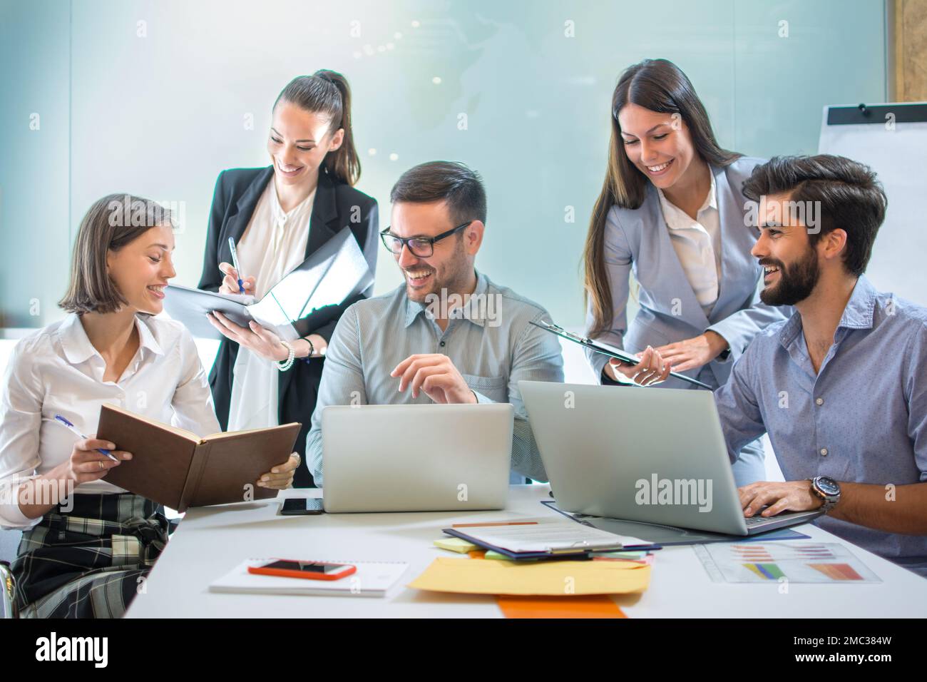 Gruppe von lächelnden, selbstbewussten Geschäftsleuten, die an einem Konferenztisch im Büro zusammenarbeiten. Stockfoto