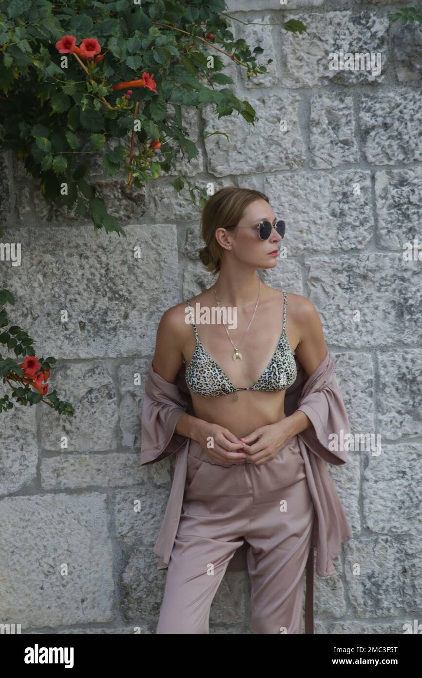 Modische Touristin in seidenbeigefarbenem einfarbigem Outfit in den Straßen der historischen Stadt Trogir, Kroatien Stockfoto