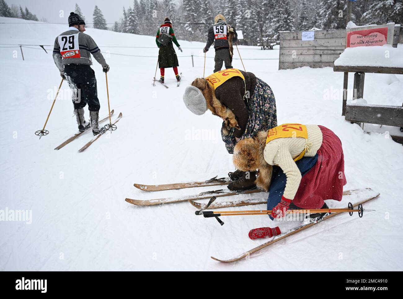 Bayern, Deutschland. 21. Januar 2023. 21. Januar 2023, Bayern, Krün: Teilnehmer schnallen sich vor dem „Nostalski“-Skirennen im Barmsee-Lift ihre Holzskier an. Mit alten Holzskiern und Schnürsenkel aus Leder, zumindest aus dem vergangenen Jahrhundert, beginnen die Teilnehmer mit einem lustigen Rennen. Foto: Angelika Warmuth/dpa Credit: dpa Picture Alliance/Alamy Live News Stockfoto