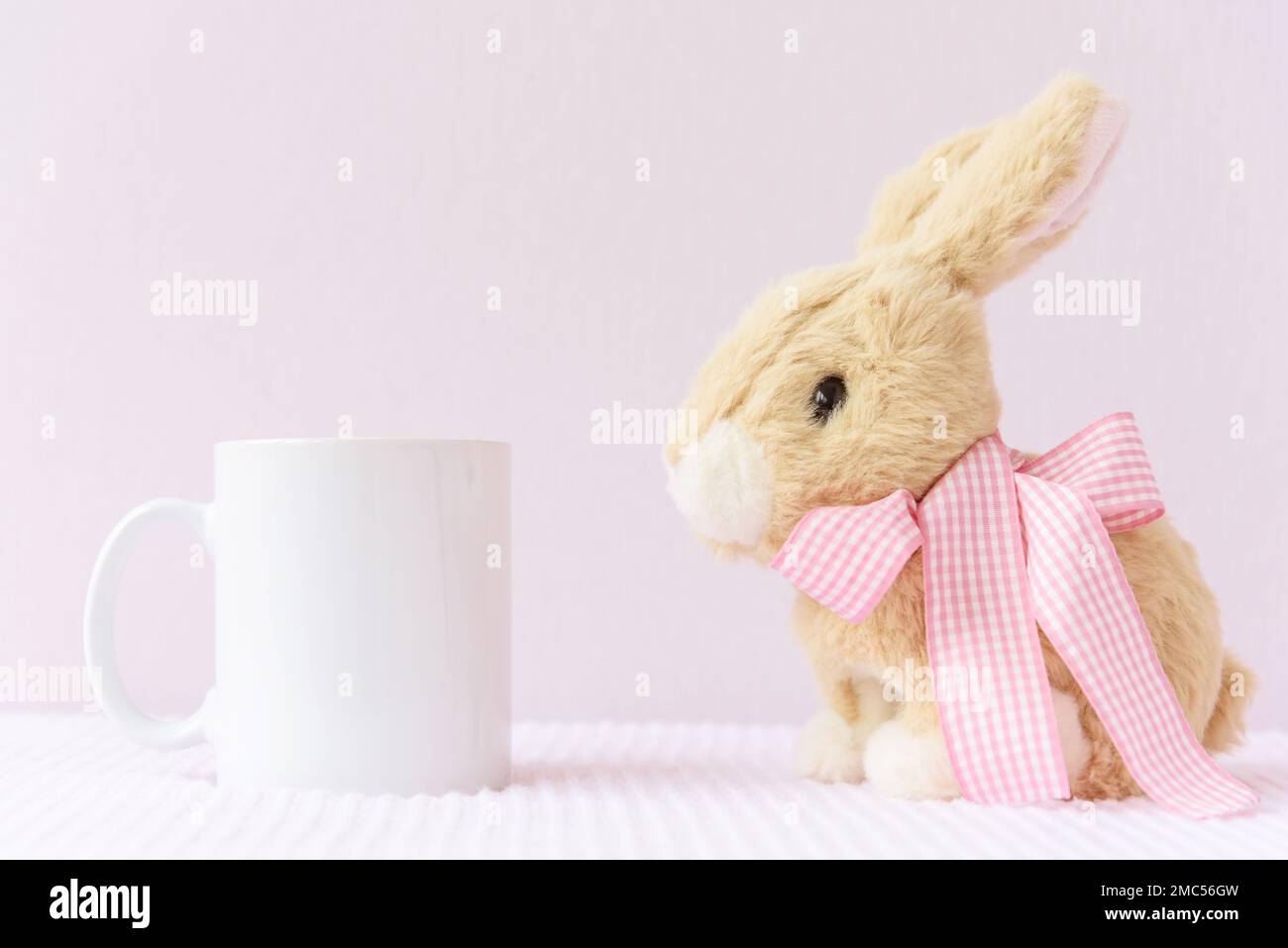 Weißer Osterbecher mit Kaninchen auf pinkfarbenem Deckelhintergrund Stockfoto
