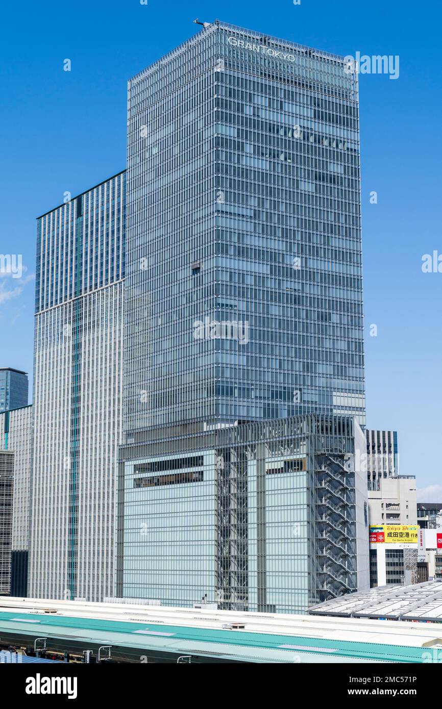 Das 205 Meter hohe Gran Tokyo North Gebäude hinter den Bahndächern des Tokio Hauptbahnhofs bei Tag vor einem klaren blauen Himmel. Stockfoto