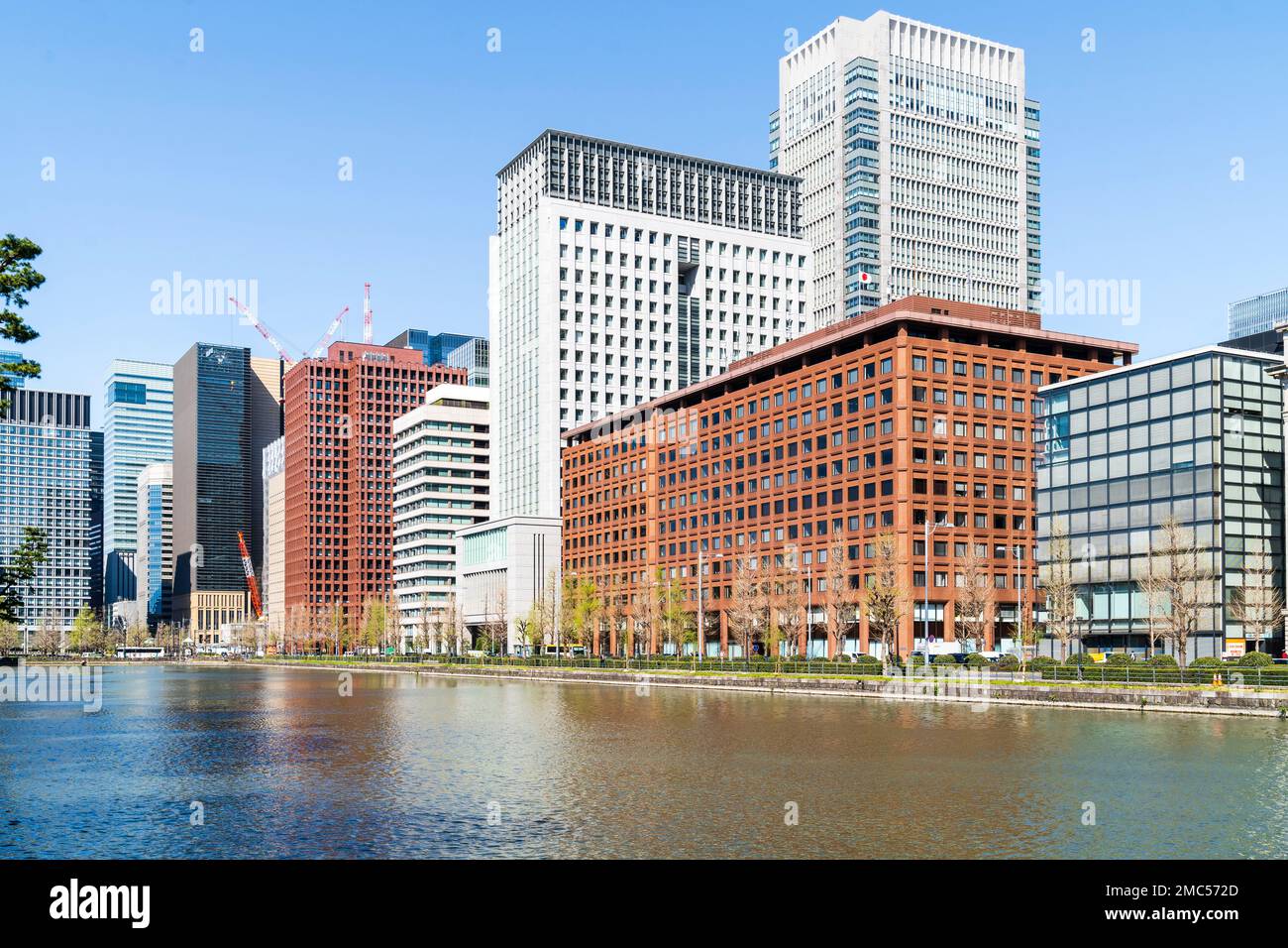 Blick über den Burggraben des Kaiserpalastes entlang der Hibiya-dori Avenue und der Büroblöcke am Ufer. Tokio. Tagsüber mit blauem Himmel. Stockfoto