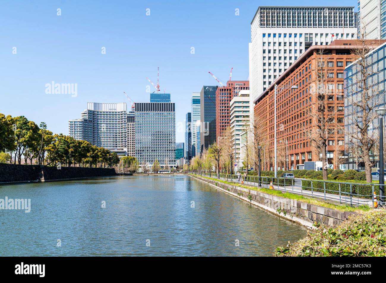 Der Burggraben des Kaiserpalastes verläuft entlang der Hibiya-dori Avenue, die auf einer Seite von Büroblöcken und am Ende vom Palace Hotel umgeben ist Tokio. Tagsüber. Stockfoto
