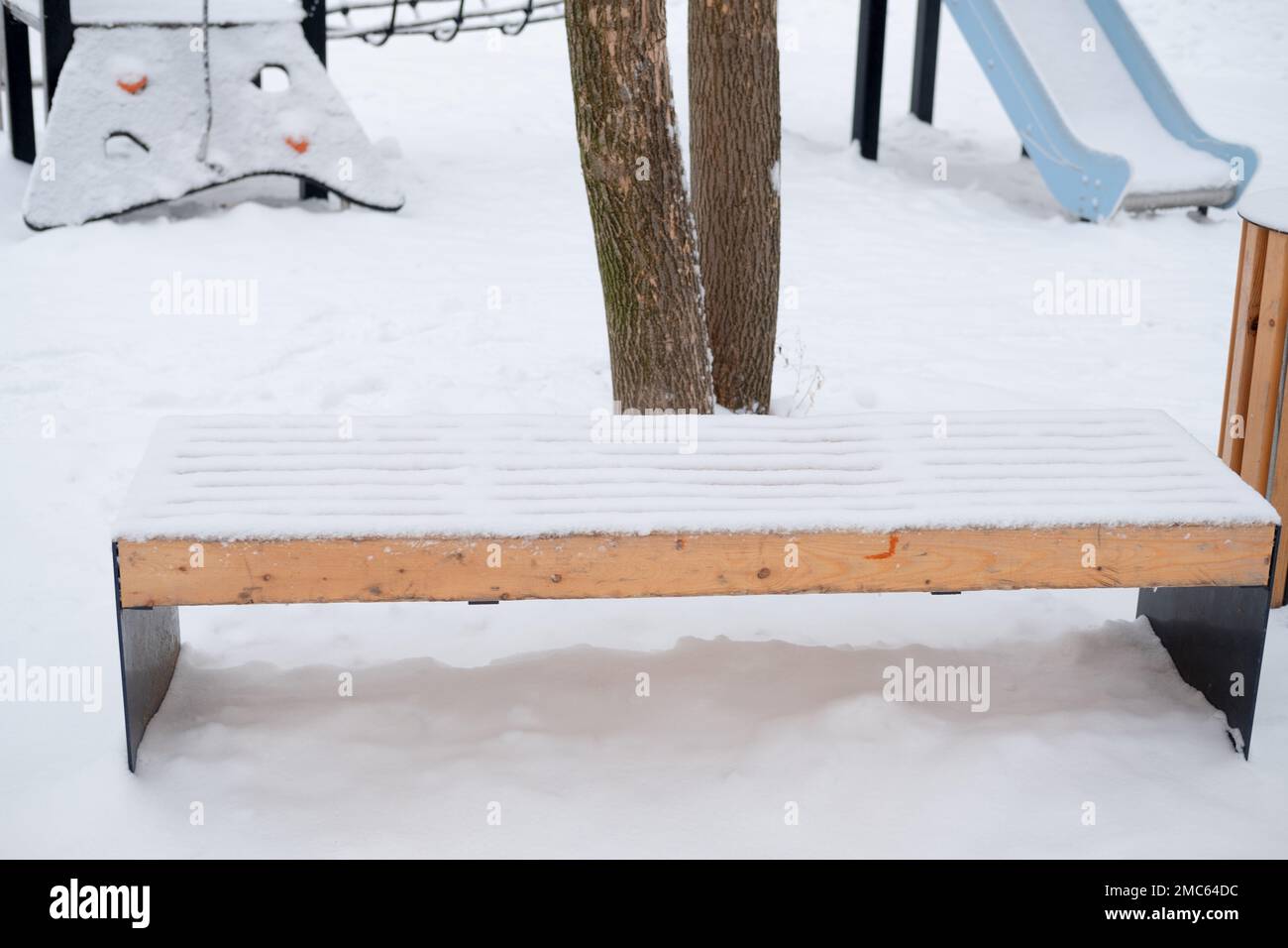 Schneebedeckte leere Bank auf der Straße, auf dem Spielplatz Stockfoto