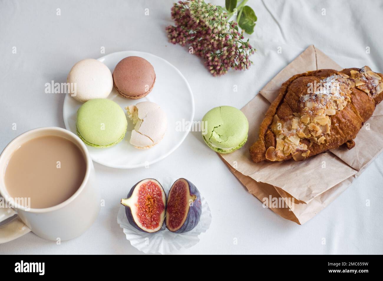 Ästhetik einer Tasse Kaffee, Feigen, einem großen Croissant und Makronen auf weißem Hintergrund, Draufsicht Stockfoto