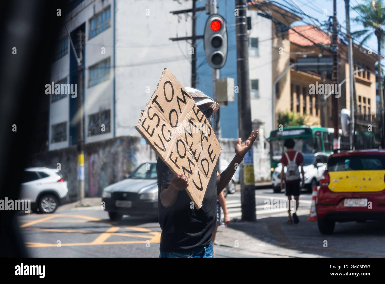 Bettler, der Geld und Essen wollte, mit einem Schild im Verkehr in Salvador, Bahia. Stockfoto