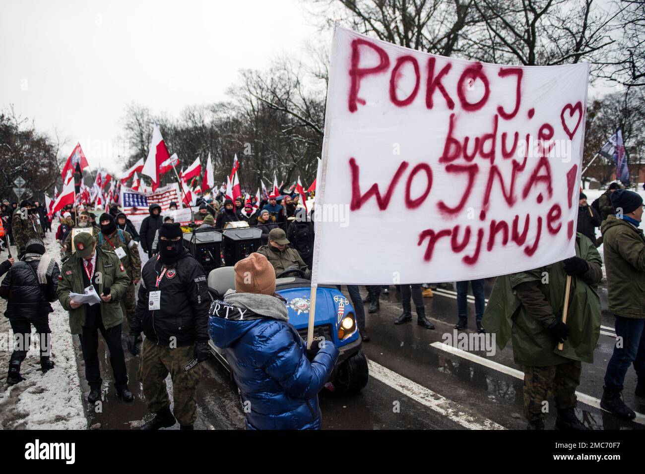 Warschau, Polen. 21. Januar 2023. Demonstranten halten während des marsches in Warschau ein Banner und schwenken polnische Flaggen. Hunderte von Menschen nahmen an einem Anti-kriegsmarsch unter dem Slogan "This is not our war" Teil, der von einer nationalistischen Gruppe namens Landsleute (Rodacy Kamraci) organisiert wurde, um gegen die Beteiligung der polnischen Regierung am Konflikt in der Ukraine zu protestieren. Die Organisation Landsleute Genossen wird in Polen von vielen als pro-russische Gruppe betrachtet. Kredit: SOPA Images Limited/Alamy Live News Stockfoto