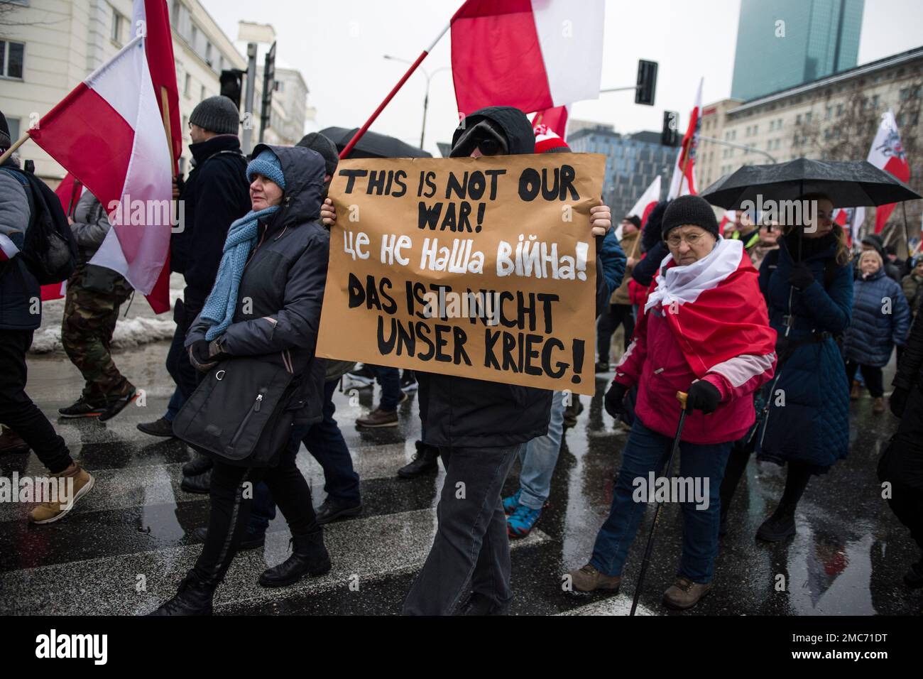 Warschau, Polen. 21. Januar 2023. Demonstranten halten während des marsches in Warschau ein Banner und schwenken polnische Flaggen. Hunderte von Menschen nahmen an einem Anti-kriegsmarsch unter dem Slogan "This is not our war" Teil, der von einer nationalistischen Gruppe namens Landsleute (Rodacy Kamraci) organisiert wurde, um gegen die Beteiligung der polnischen Regierung am Konflikt in der Ukraine zu protestieren. Die Organisation Landsleute Genossen wird in Polen von vielen als pro-russische Gruppe betrachtet. Kredit: SOPA Images Limited/Alamy Live News Stockfoto