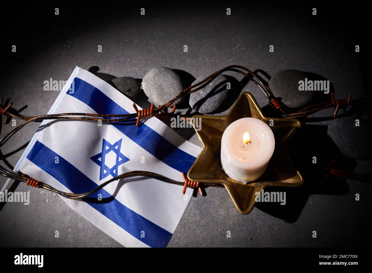Brennende Kerze, Stacheldraht, Flagge Israels auf dunklem Hintergrund. Holocaust-Gedächtnisfeiertag Stockfoto
