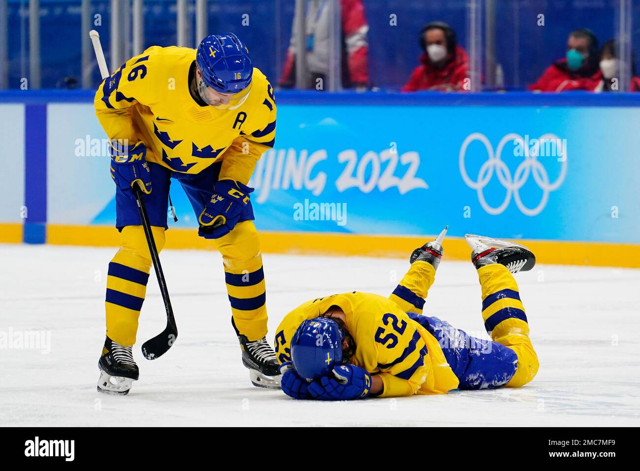 Sweden's Philip Holm (52) is attended to by Marcus Kruger (16) after Holm was injured during a preliminary round men's hockey game against Finland at the 2022 Winter Olympics, Sunday, Feb. 13, 2022, in Beijing. (AP Photo/Matt Slocum) Stockfoto