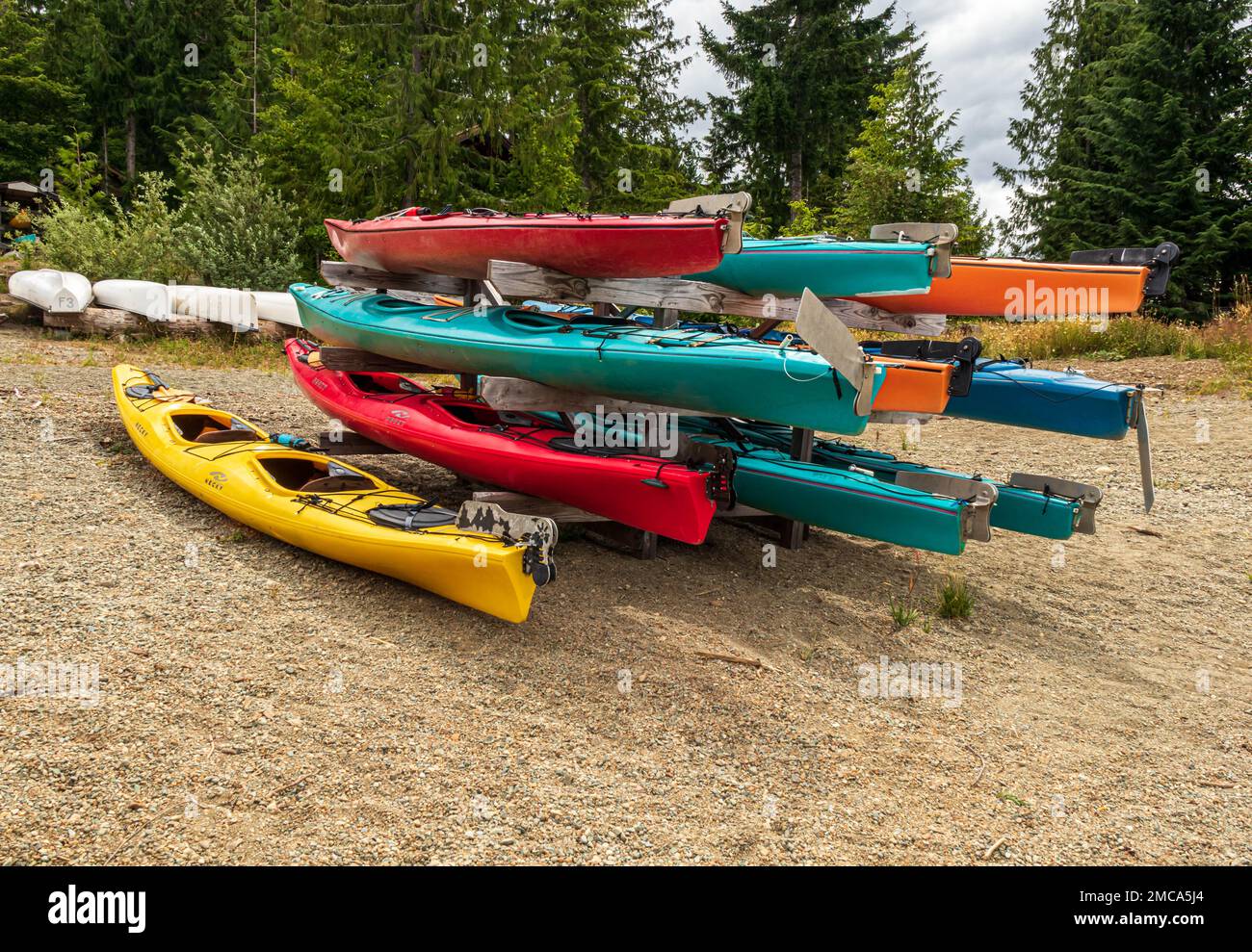 Farbenfrohe Kajaks, die auf den Sommer warten, am Strand von Strathcona Lake, B.C. Stockfoto