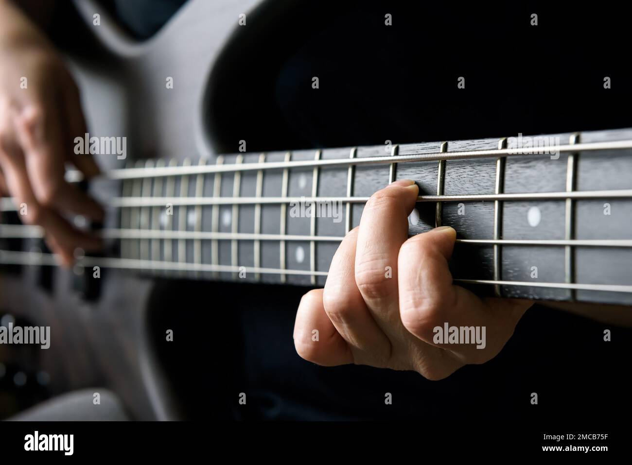 Bass Gitarrenspieler Hand-Nahaufnahme, Lern- und Übungsthema. Elektrische Bassgitarre, Livemusik und Können. Nahaufnahme der Gitarrenflosse Stockfoto