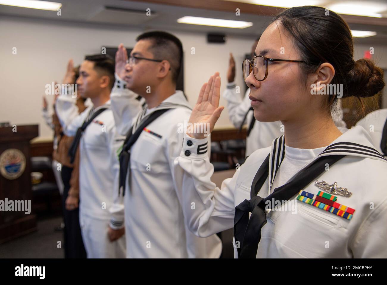 Matrosen und Familienmitglieder aus Sasebo schwören den USA bei einer Einbürgerungszeremonie bei Commander, Fleet Activities Sasebo am 29. Juni 2022 den Einbürgerungseid. USA Citizenship and Immigration Services und das regionale Legal Service Office Western Pacific arbeiteten zusammen, um die Einbürgerungszeremonie bei CFAS durchzuführen, die es Seeleuten ermöglichte, US-Bürger zu werden. Stockfoto