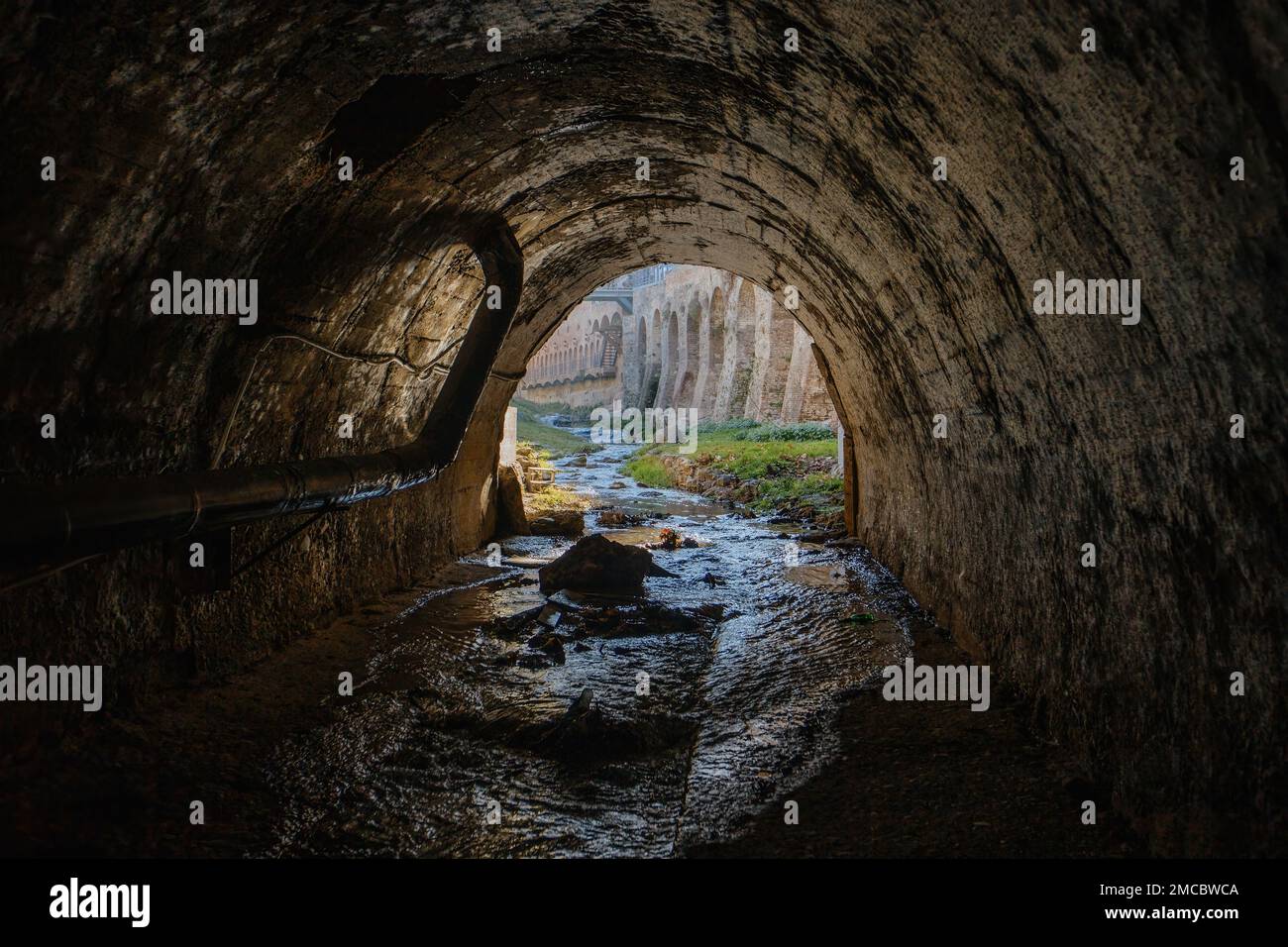 Verlassen Sie den gewölbten Abwassertunnel. Unterirdischer Fluss, Blick vom Inneren des Kanalisationstunnels. Stockfoto