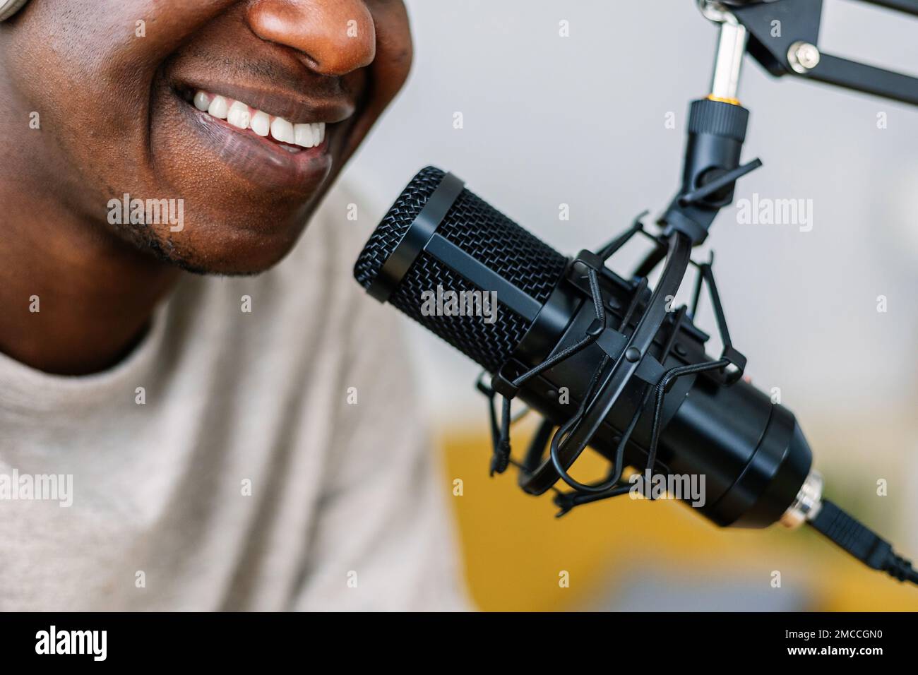Lächelnder junger afrikanischer Mann, der im Internet Radio-Podcasts aufnimmt Stockfoto