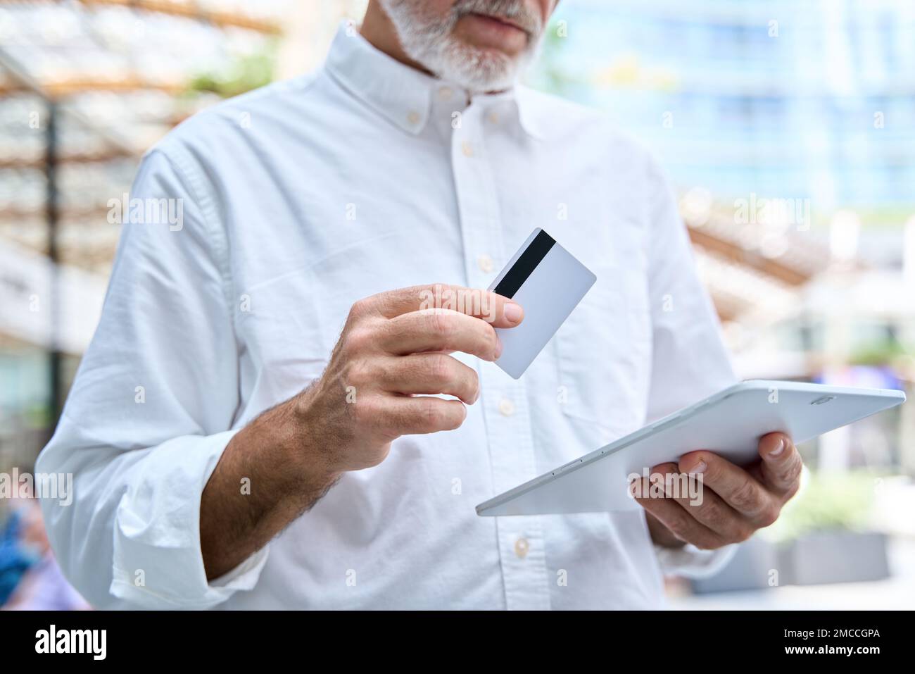 Ein alter Geschäftsmann mit digitalem Tablet und Kreditkarte. Stockfoto