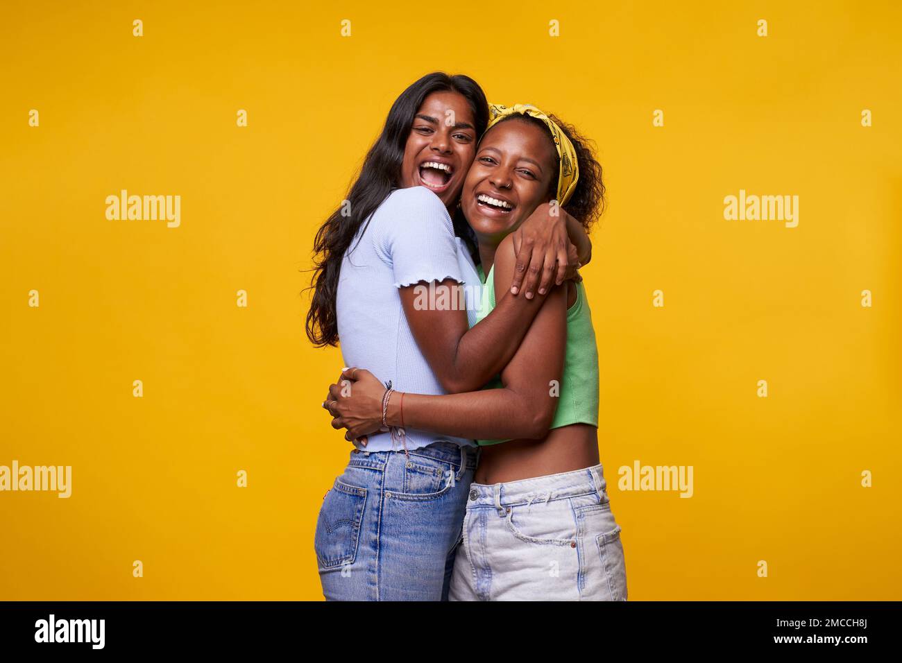 Zwei Diversität ziemlich positive Mädchen mit einem Lächeln, isoliert auf gelbem Hintergrund. Stockfoto