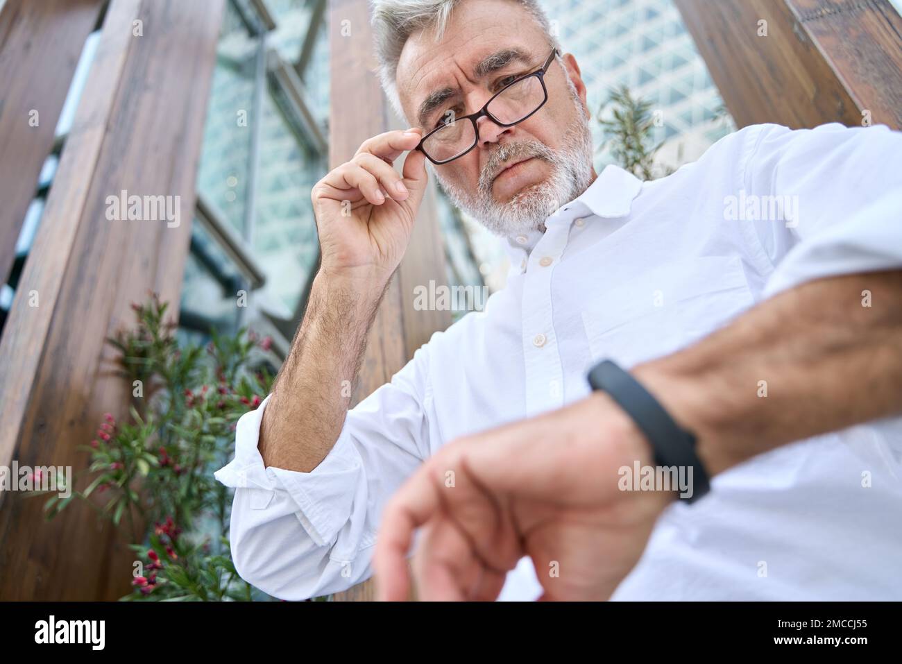 Beschäftigter älterer Geschäftsmann, der sich draußen eine Armbanduhr anschaut. Stockfoto