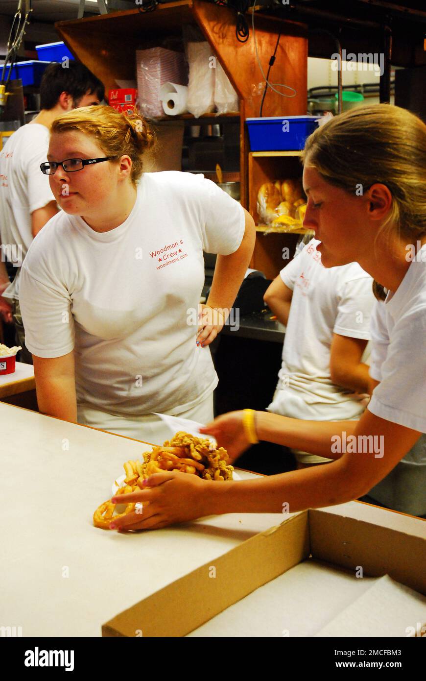Junge weibliche Arbeiterinnen bereiten in einem Café an der Küste von Massachusetts im Rahmen ihrer Sommerarbeit eine Bestellung von Meeresfrüchten zu Stockfoto