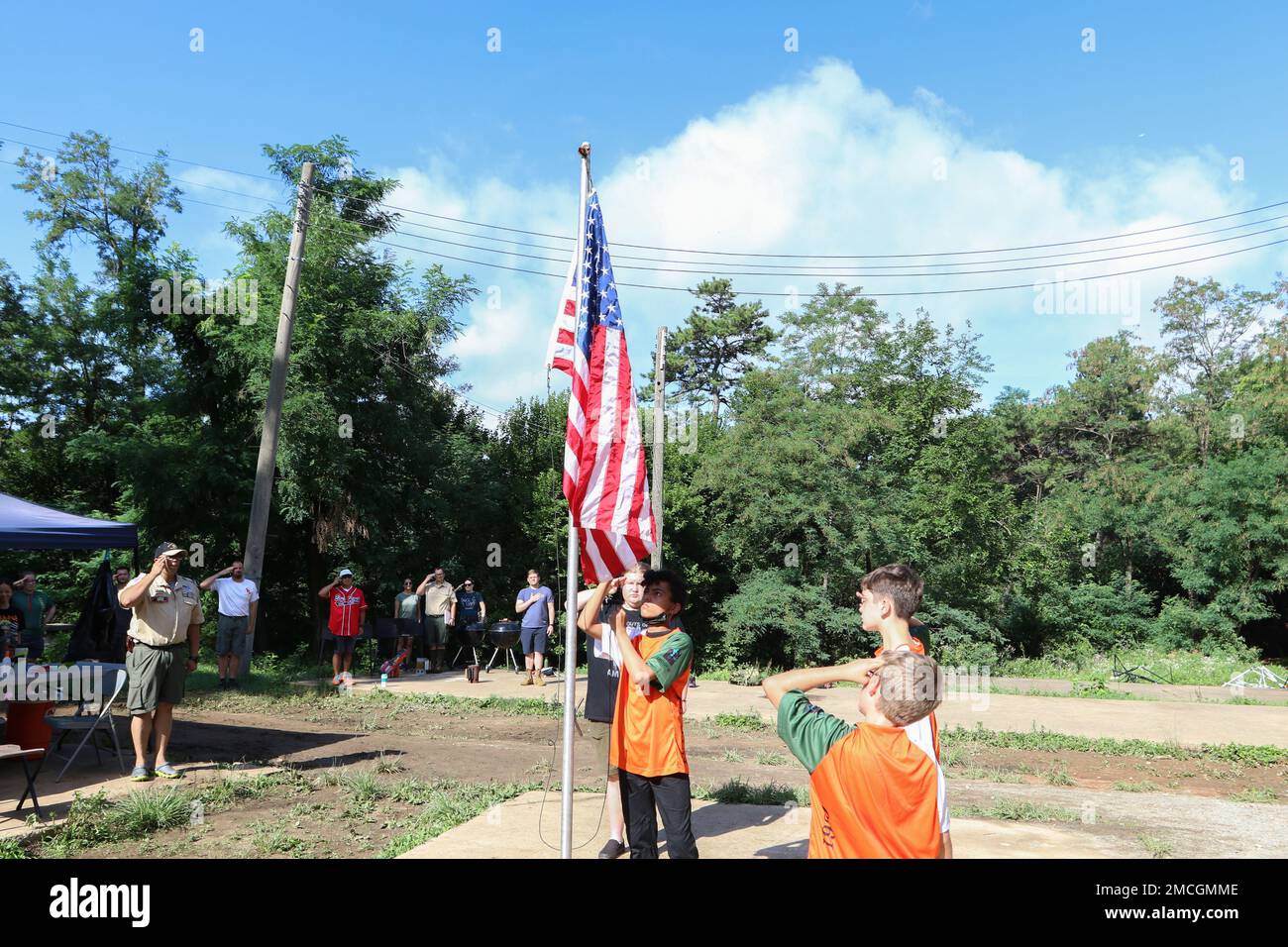 Die Späher salutieren und heben die Flagge, bevor sie mit ihrem morgendlichen Training beginnen. Headquarters Support Company, Headquarters and Headquarters Battalion, Eighth Army, unterstützte das zweite jährliche Asia West District Tiger Merit Badge University, Boy Scouts of America Event von Juni 27 bis Juli 1. Stockfoto