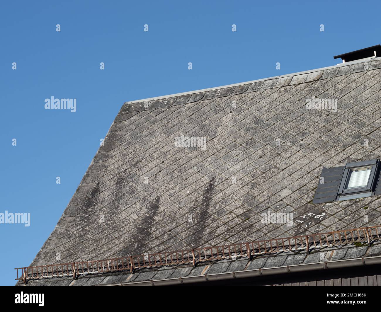 Gefährliche Asbestplatten als Dachziegel eines Wohngebäudes. Verwitterte Fassade eines Hauses. Das Material wurde in der DDR verwendet. Stockfoto