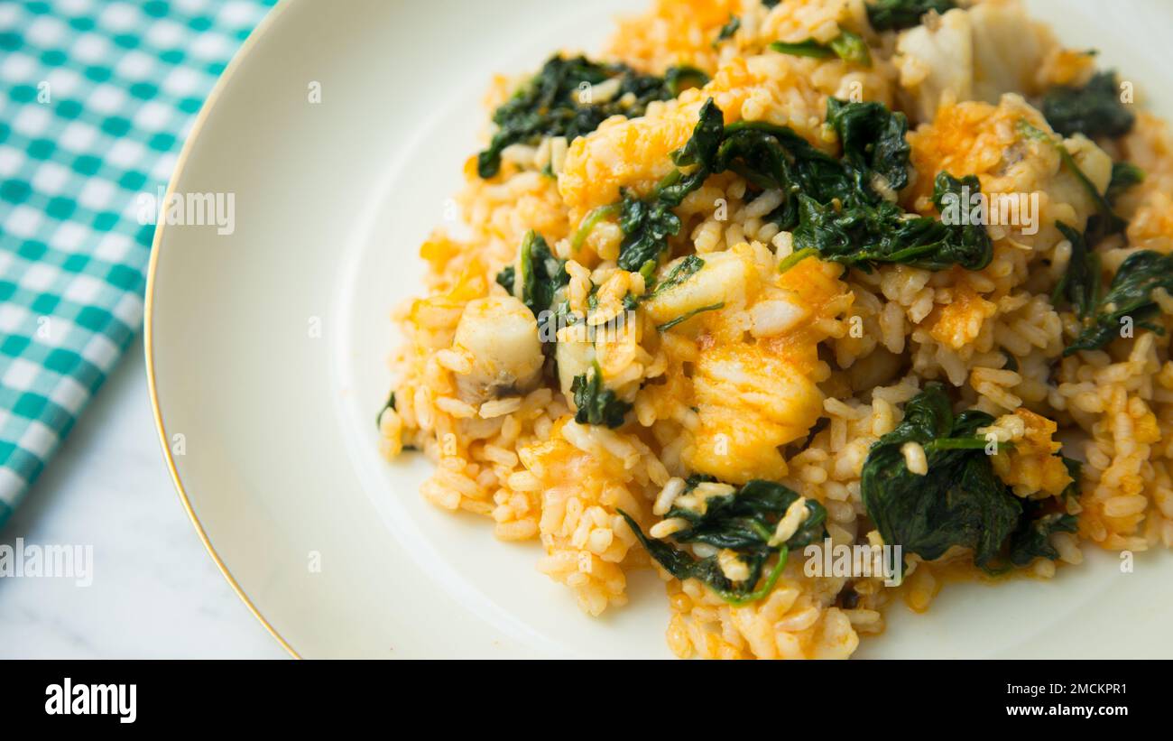 Originales spanisches Paella-Rezept mit Mönchsfisch und Spinat Stockfoto