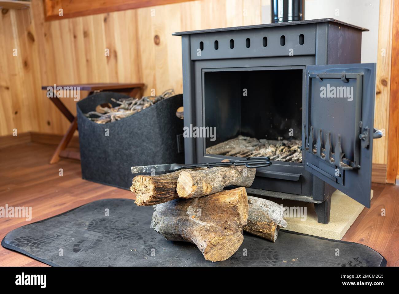 Rustikaler Holzofen mit Holzstämmen, der in den Kamin eingeführt werden kann. Stockfoto