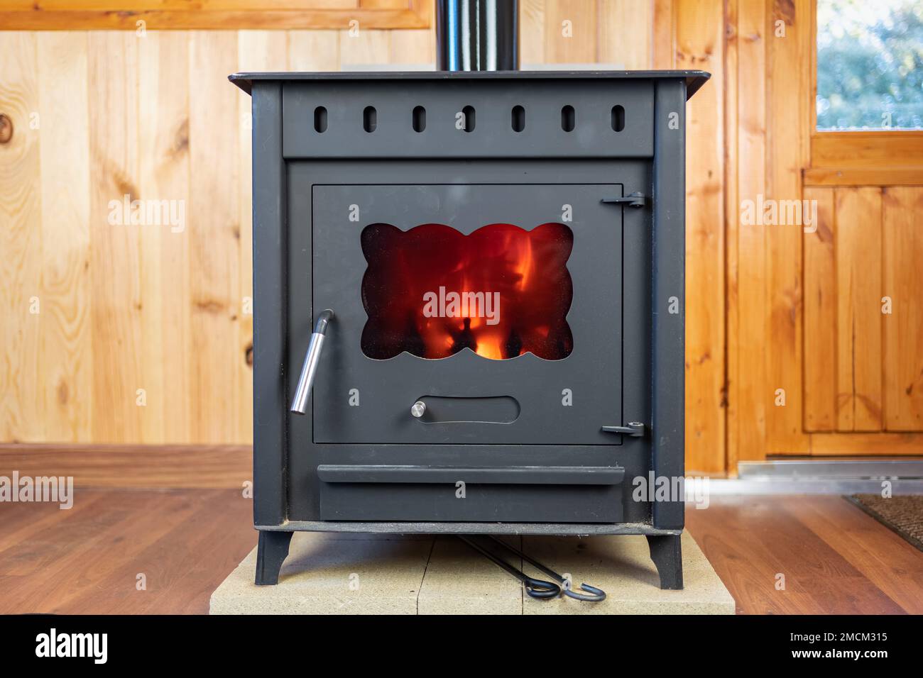 Rustikaler gusseiserner Ofen mit Feuer im Inneren, um das Haus zu heizen. Stockfoto