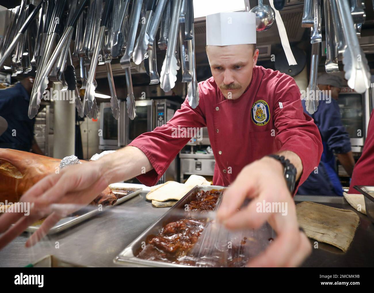 PHILIPPINE SEA (6. Juli 2022) Culinary Specialist Seaman Brock McDorman aus San Marcus, Texas, legt Plastikfolie über einen Behälter mit Rippenspitzen in der Bordküche an Bord der Arleigh Burke-Klasse-Guided-Missile Destroyer USS Benfold (DDG 65). Benfold ist dem Kommandeur, der Task Force (CTF) 71/Destroyer Squadron (DESRON) 15, der größten nach vorn eingesetzten DESRON der Marine und der Hauptstreitkräfte der US-7.-Flotte zugewiesen. Stockfoto