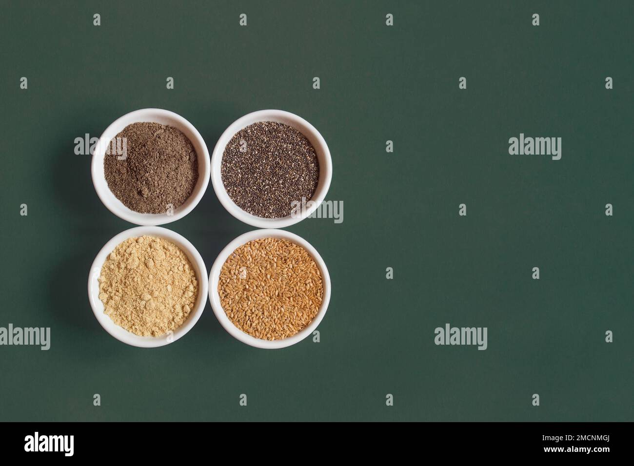 Chia- und Leinsamen sowohl gemahlen als auch ganz auf weißen Keramikschüsseln auf farbenfrohem Studiohintergrund mit Kopierbereich. Gesundes Saatgut zu essen. Stockfoto