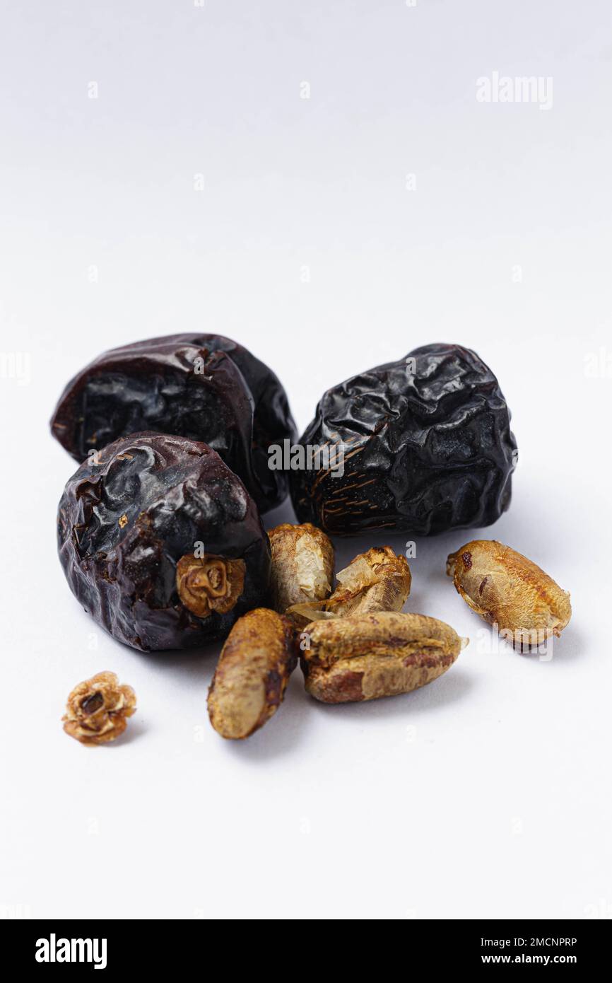 Die satte dunkelbraune Farbe und die einzigartige Form der Ajwa-Daten heben sich vor dem weißen Hintergrund hervor Stockfoto