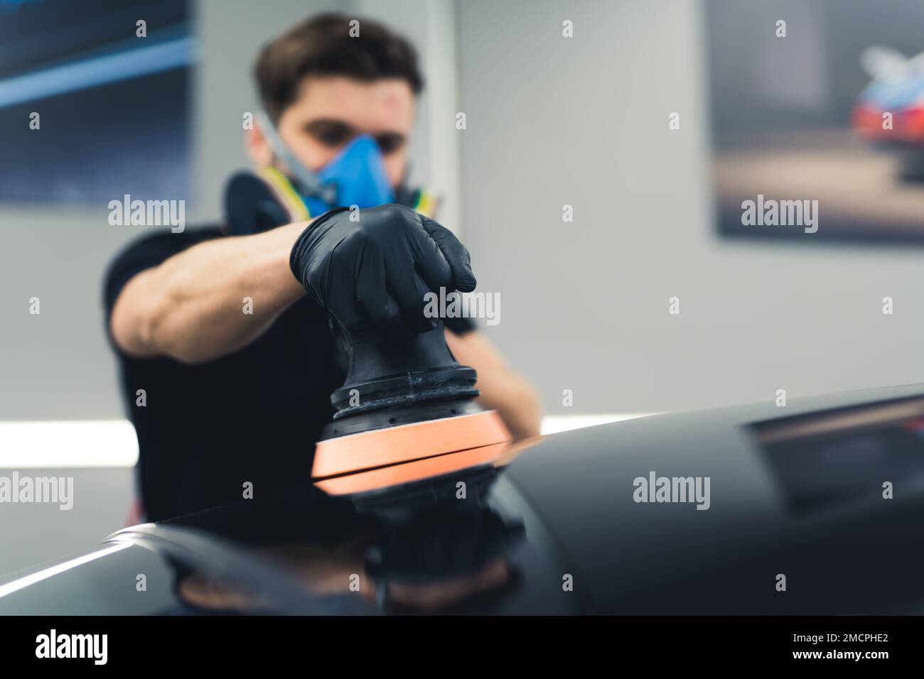 Fahrzeugdetails und Polierkonzept. Professioneller Kraftfahrzeugarbeiter mit Orbitalpolierer in der Hand. Indoor-Aufnahme. Hochwertiges Foto Stockfoto