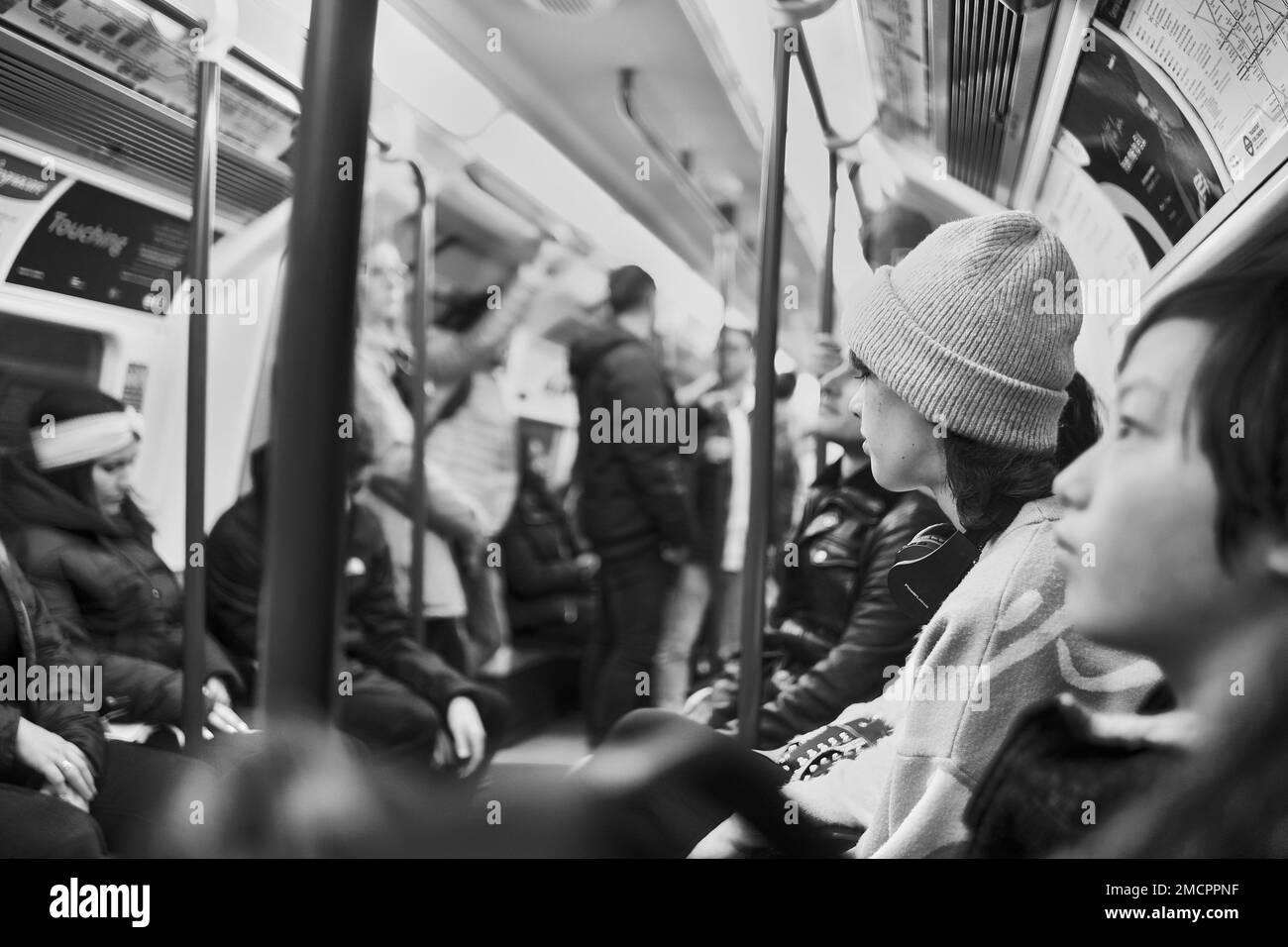 Schwarzweiß, natürliche Aufnahme von Passagieren in der Londoner U-Bahn, in einem belebten Zugwaggon; unglückliche Pendler stehen und sitzen, keine Interaktion Stockfoto