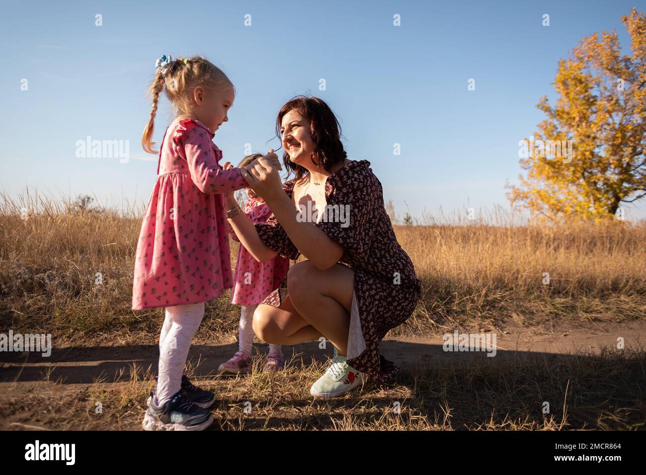 Mom und die Zwillinge setzten sich unter freiem Himmel. Das Konzept des Supports. Frauentag Stockfoto