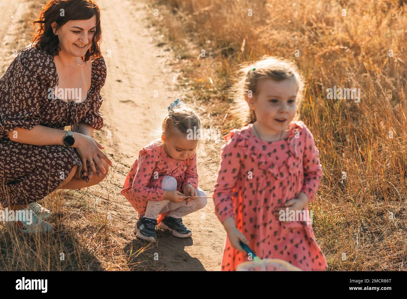 Mütter und Zwillingsmädchen fangen Insekten im Freien mit Netzen und studieren die Natur mit Kindern Stockfoto