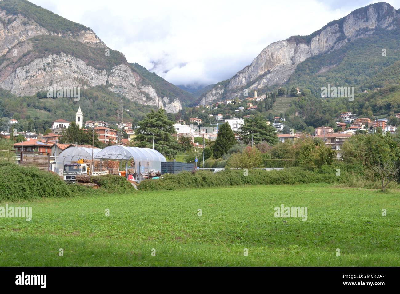 Panoramablick auf die weitläufige grüne Umgebung der italienischen Alpen in der Provinz Lecco. Die Stadt Calolziocorte. Stockfoto