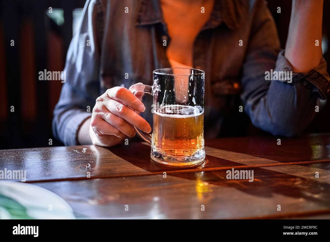 Eine Frau, die eine Tasse Bier vom Fass in der Hand hält. Erholen Sie sich mit Getränken, Verkostung, Menschen- und Urlaubskonzept. Stockfoto