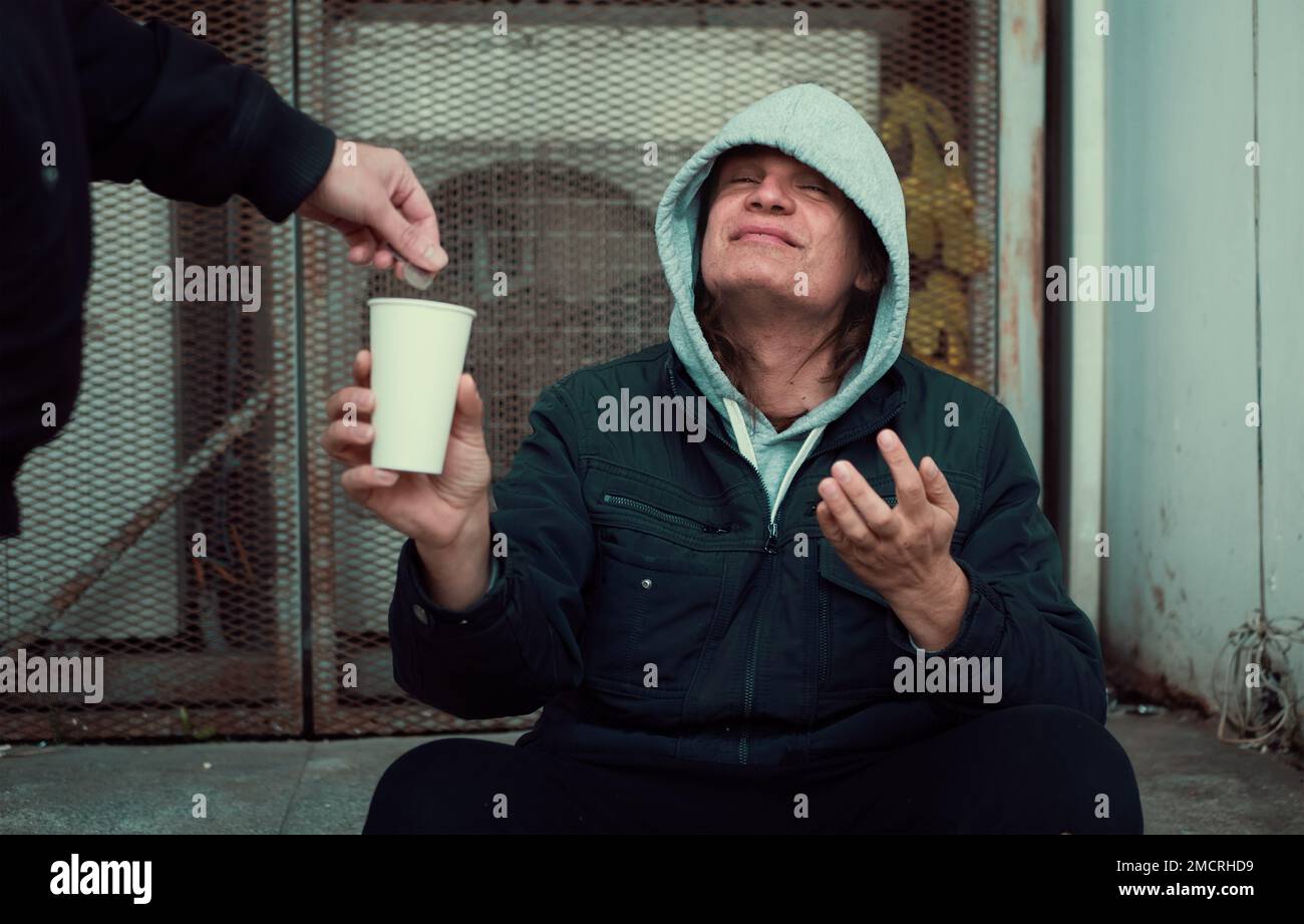 Ein Obdachloser sitzt auf einer Treppe und bittet um Hilfe und Geld. Stockfoto