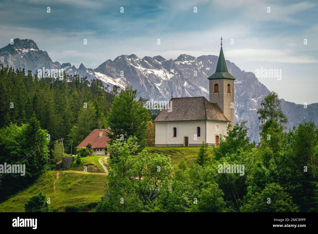 Slowenische Berglandschaft und süße kleine Kirche auf dem Hügel. Die Kirche Sveti Duh und die Kamnik-Savinja-Alpen im Hintergrund, Slowenien, Europa Stockfoto